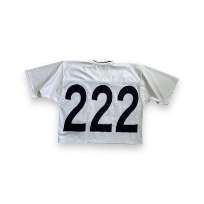 The back of a cream mesh jersey displaying a large “222” in bold black numbers, outlined in pink, centered on the jersey.