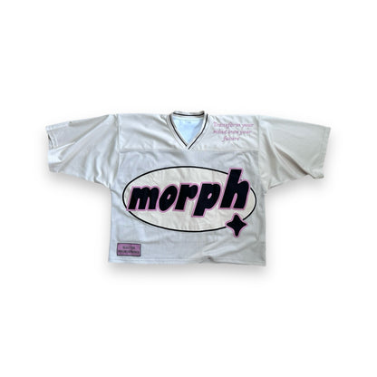 A cream mesh jersey with pink detailing along the sleeves, featuring a large oval-shaped logo on the front that reads “morph” in bold. The phrase “Transform your mind own your future” is placed in the upper right corner. The phrase “Built on Perseverance” is placed on a woven label in the lower left corner. 