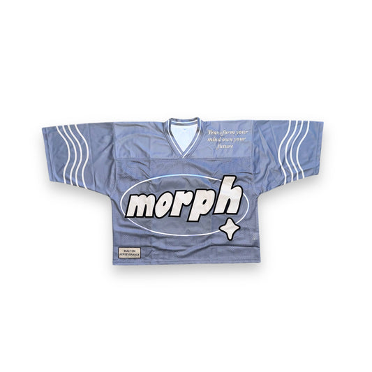 A grey mesh jersey with cream detailing along the sleeves, featuring a large oval-shaped logo on the front that reads “morph” in bold. The phrase “Transform your mind own your future” is placed in the upper right corner. The phrase “Built on Perseverance” is placed on a woven label in the lower left corner. 